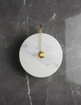Unlit marble disc on a gold arm against grey veined stone
