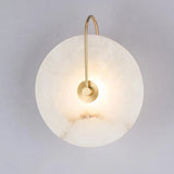 Marble disc sconce on a gold curved arm against a pale wall