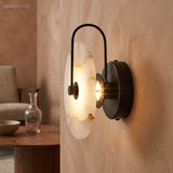 Black arm marble sconce lit beside a wooden table and glass vase