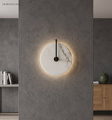Marble disc sconce glowing softly on a grey stone feature wall