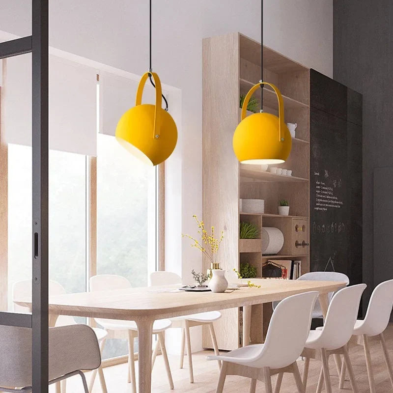 Metal ball pendant light hanging low over a neutral styled interior