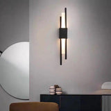 Black linear sconce lit on a pale wall above a slatted cabinet