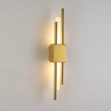 Brushed gold twin bar sconce lit against a plain grey background