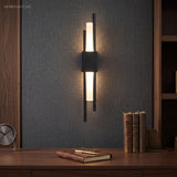 Black twin bar sconce lit on dark panelling above a sideboard