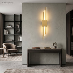 Gold linear sconce lit on a pale wall above a console table