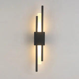 Matte black twin bar sconce lit against a plain grey background