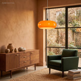 Orange glass pendant light over a sideboard in a warm terracotta living room