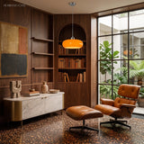 Orange glass pendant light in a walnut-panelled reading room with shelves