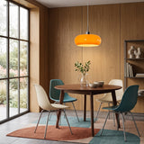 Orange glass pendant light above a round dining table with blue chairs