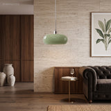 Green glass pendant light in a cosy living room with sofa and plant