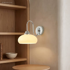 Chrome bracket milk glass wall sconce mounted near oak shelving