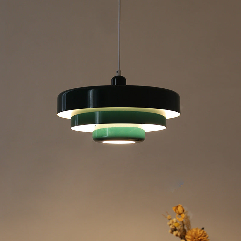 Black tiered pendant light with mint green inner rings, lit from within