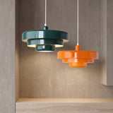 Dark green and orange tiered pendants above a timber bench and concrete wall