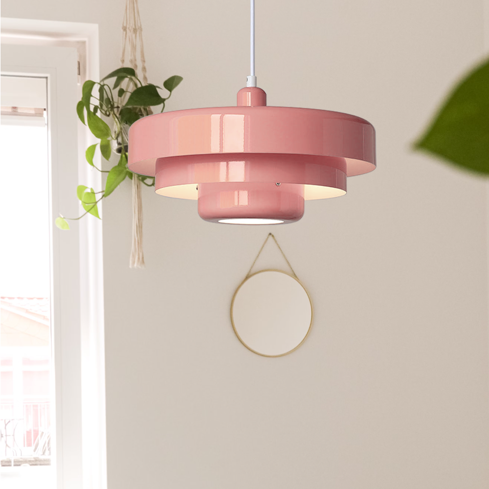 Pink tiered pendant light beside a window with trailing plants and a round mirror