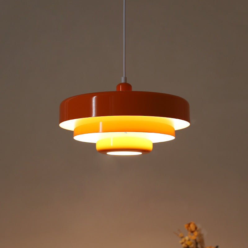 Rust red tiered pendant light with a glowing yellow inner reflector