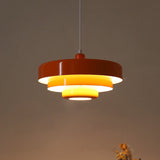 Rust red tiered pendant light with a glowing yellow inner reflector