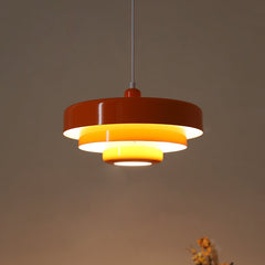 Rust red tiered pendant light with a glowing yellow inner reflector