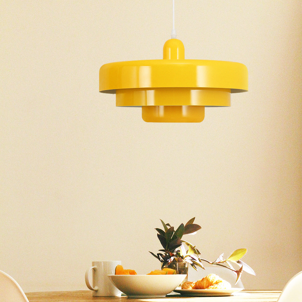 Yellow tiered pendant light above a table set with a bowl of oranges