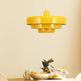 Yellow tiered pendant light above a table set with a bowl of oranges