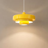 Yellow tiered pendant light casting a warm cone of light down a beige wall
