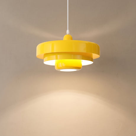 Yellow tiered pendant light casting a warm cone of light down a beige wall