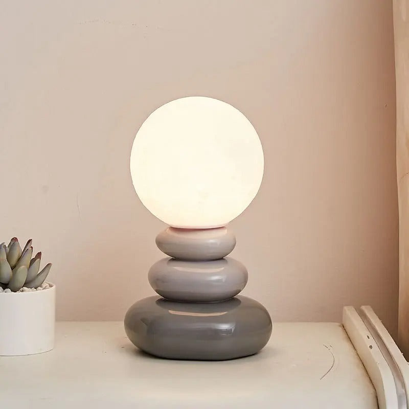 Grey stacked lamp glowing against a soft pink painted wall
