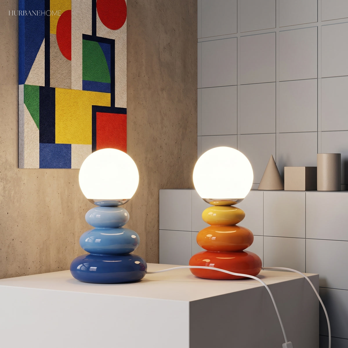 Blue and orange stacked lamps lit beside a bold geometric artwork
