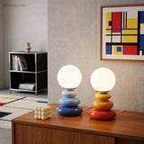 Blue and orange lamps on a walnut sideboard below a geometric print