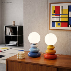 Blue and orange lamps on a walnut sideboard below a geometric print