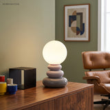 Grey stacked lamp lit on a sideboard in a green painted room