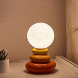 Orange and yellow stacked lamp lit against a warm pink wall