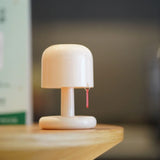 Cream mushroom shaped cordless table lamp with a red pull tag on timber