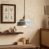 Pale blue ceramic pendant lit above a shelf and framed fern print
