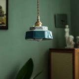 Teal ceramic pendant lit in a green room beside a cabinet
