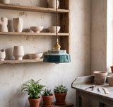 Teal stepped ceramic pendant lit beside shelves of pots