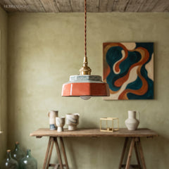 Terracotta ceramic pendant lit above a timber work table