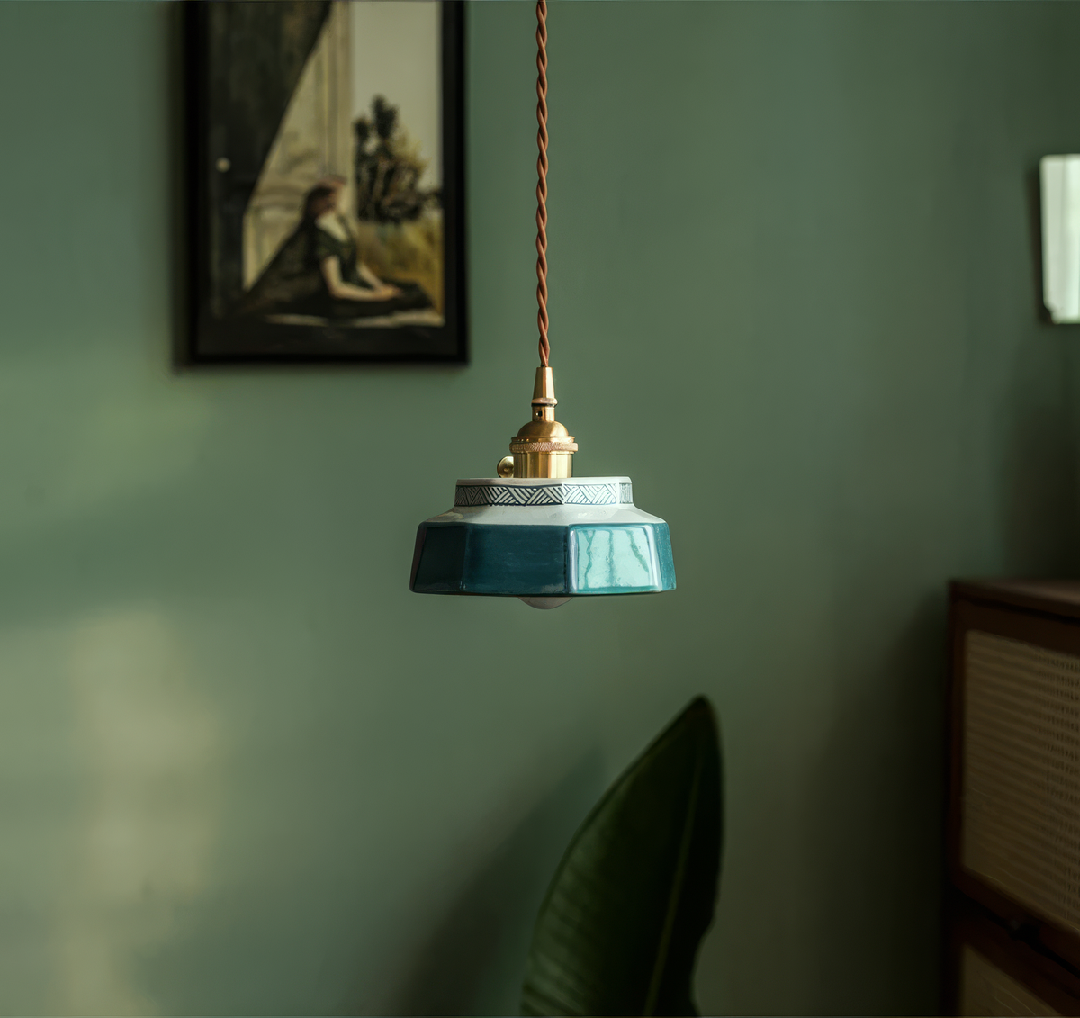 Teal stepped ceramic pendant lit warm on a green painted wall