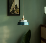 Teal stepped ceramic pendant lit warm on a green painted wall