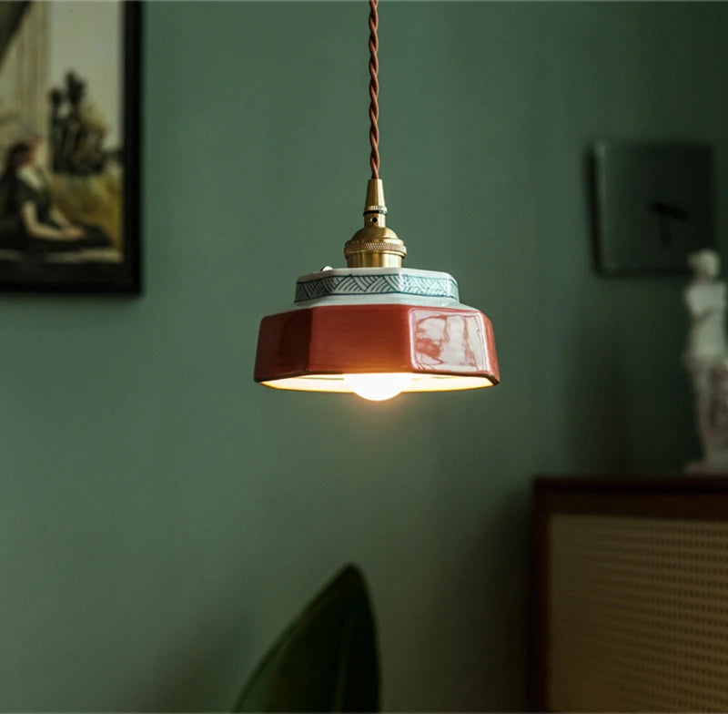 Terracotta ceramic pendant lit warm above a framed print