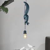 Blue squirrel pendant lit beside a large leafy houseplant