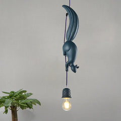 Blue squirrel pendant lit warm beside a tall potted plant