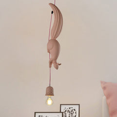 Pink squirrel pendant lit above a stack of framed pictures