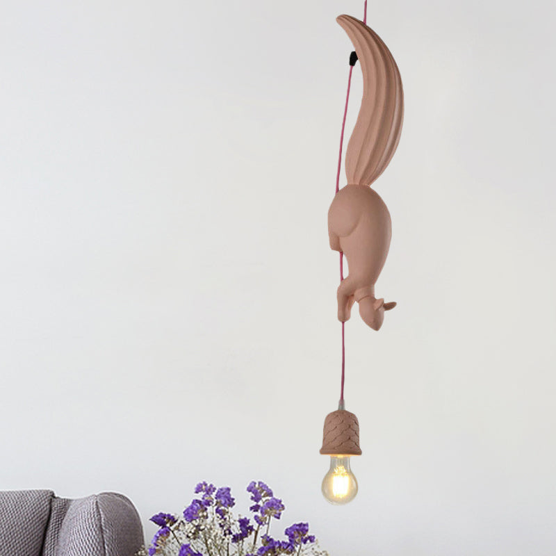 Pink squirrel pendant lit above a grey knitted throw and flowers