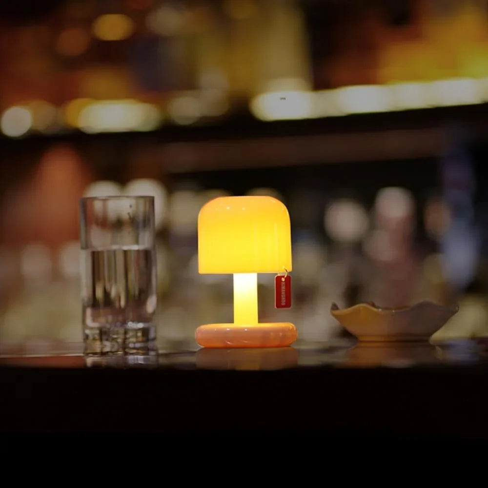Small orange mushroom table lamp glowing on a dark bar counter