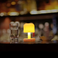 Small orange mushroom table lamp glowing on a dark bar counter