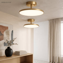 Two gold disc ceiling lights lit above a console and artwork
