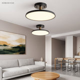 Two black disc ceiling lights lit above a sofa and coffee table