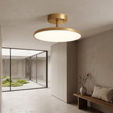 Gold disc ceiling light lit above a hallway bench and vase