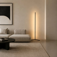 Black corner floor lamp lighting a sofa nook below a bold framed print