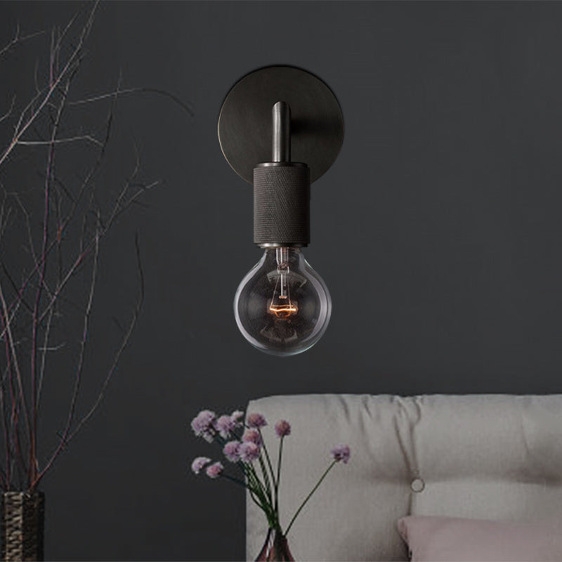 Black sconce above a pale sofa with dried branches in a vase